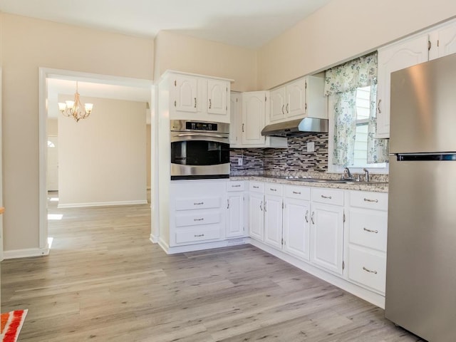 411 4th St, Darlington, PA 16115 - kitchen with appliances with stainless steel finishes, white cabinets, decorative backsplash, a chandelier, and light wood-style flooring
