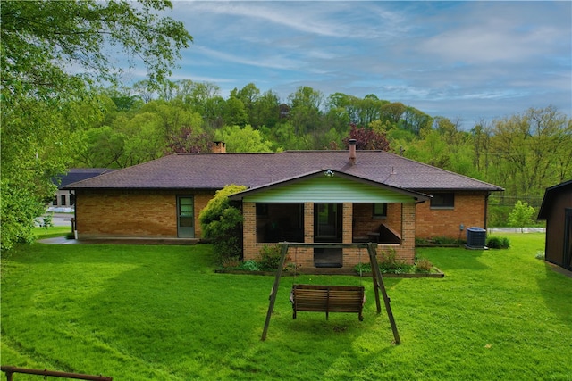 back of house featuring central AC, a yard, brick siding, and a shingled roof