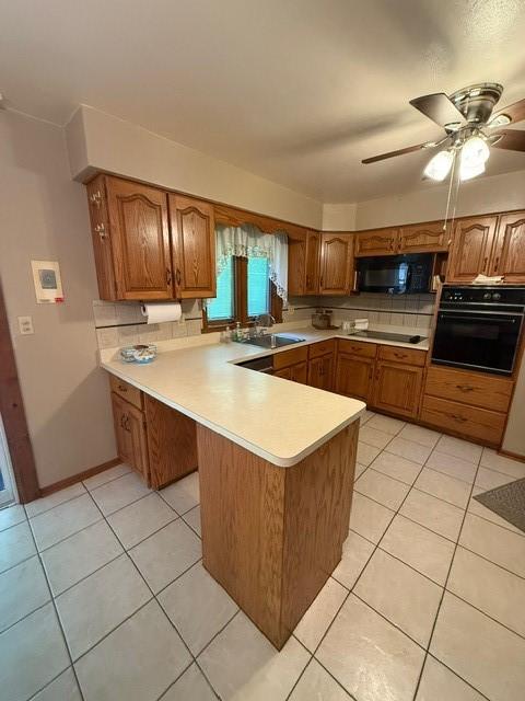 kitchen with black appliances, light countertops, brown cabinets, a peninsula, and light tile patterned floors