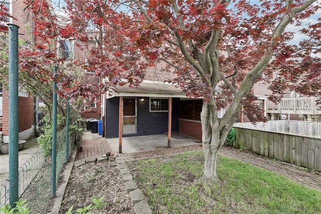 rear view of property featuring fence, a patio, and brick siding