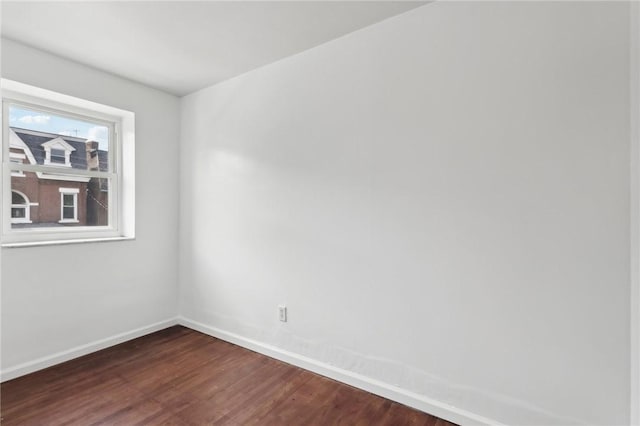 empty room with dark wood-type flooring and baseboards