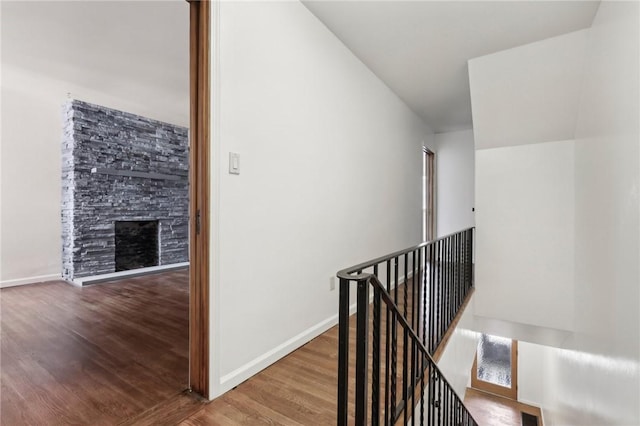 hall featuring an upstairs landing, wood finished floors, and baseboards