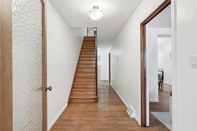 hall featuring wood finished floors, stairs, and baseboards