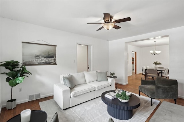 living area featuring wood finished floors, a chandelier, ceiling fan, and baseboards