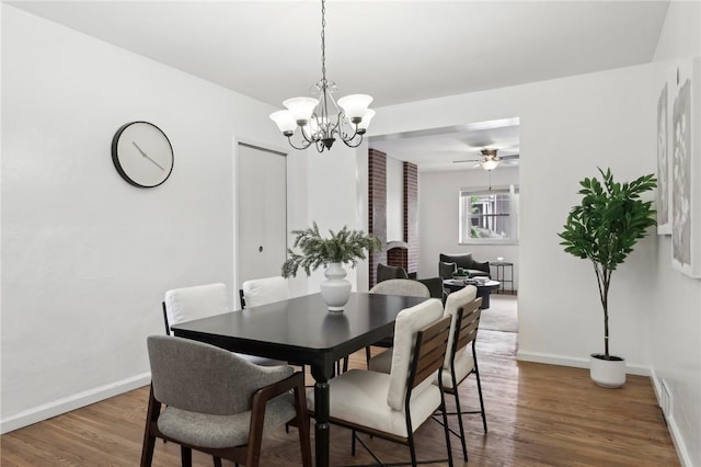 dining space featuring baseboards, wood finished floors, a chandelier, and ceiling fan