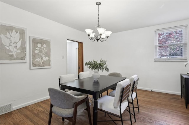 dining area with a chandelier, wood finished floors, and baseboards