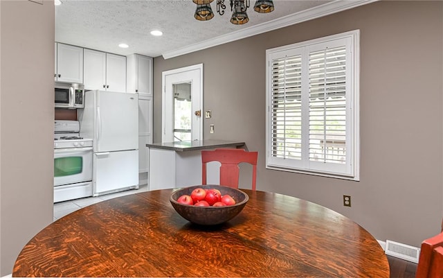 kitchen featuring white appliances, a textured ceiling, recessed lighting, crown molding, and a chandelier