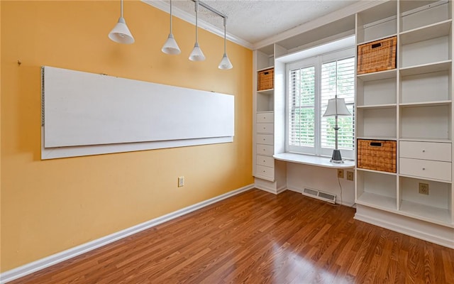 spare room featuring ornamental molding, wood finished floors, a textured ceiling, and baseboards