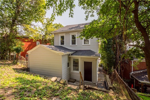 back of property with a shingled roof, fence, and entry steps