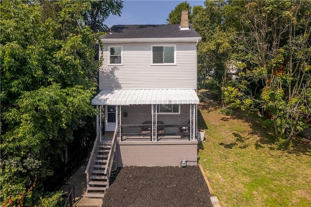 view of front of home with a front lawn, a chimney, and stairway