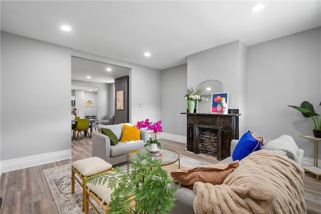 living room with baseboards, wood finished floors, recessed lighting, and a high end fireplace