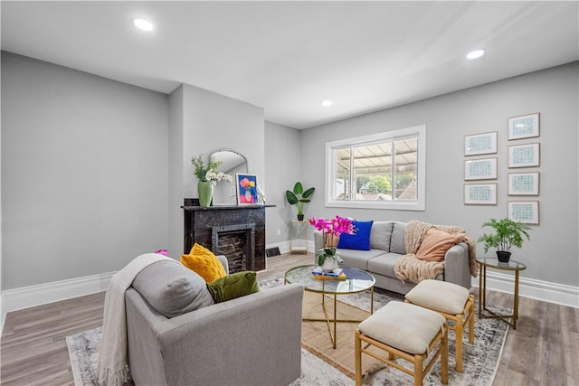living room featuring baseboards, a fireplace, wood finished floors, and recessed lighting