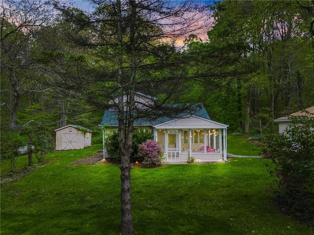 192 Wilkins Hollow Rd, Addison Twp, PA 15411 - back of house at dusk with a storage unit, a yard, a sunroom, and an outdoor structure