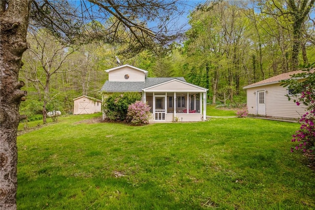 192 Wilkins Hollow Rd, Addison Twp, PA 15411 - rear view of property featuring a sunroom, a storage unit, an outbuilding, a yard, and a shingled roof