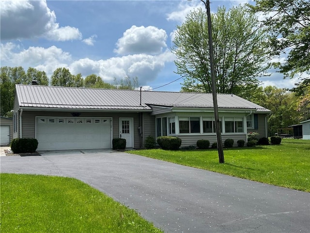 ranch-style house featuring asphalt driveway, a front yard, an attached garage, and metal roof