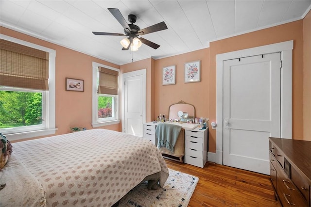 bedroom with wood-type flooring, a ceiling fan, and ornamental molding