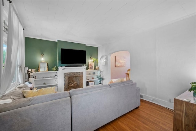 living room featuring wood finished floors, a fireplace, crown molding, and baseboards