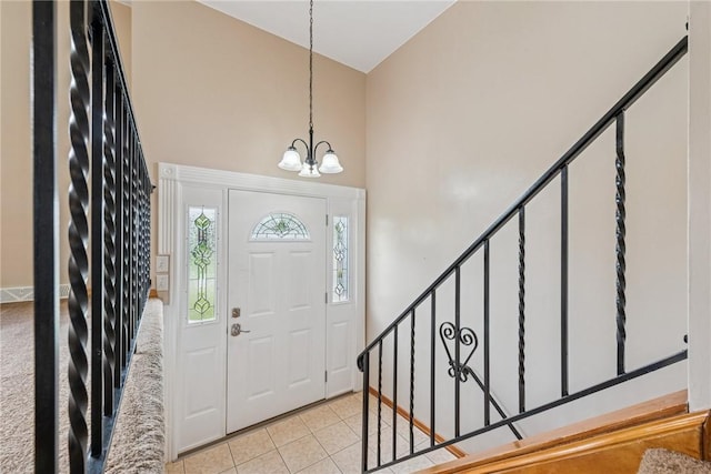 foyer with a high ceiling, a chandelier, light tile patterned flooring, and stairs