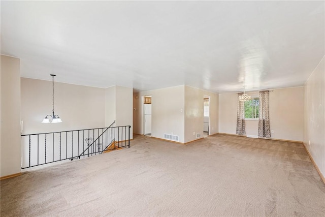 carpeted spare room with a chandelier and baseboards