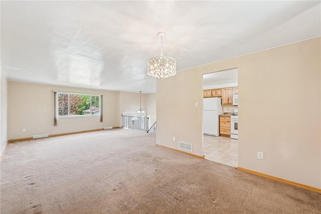 unfurnished living room with a chandelier, baseboards, and light carpet