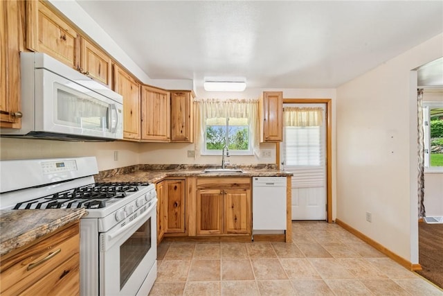 kitchen with white appliances, a sink, and baseboards