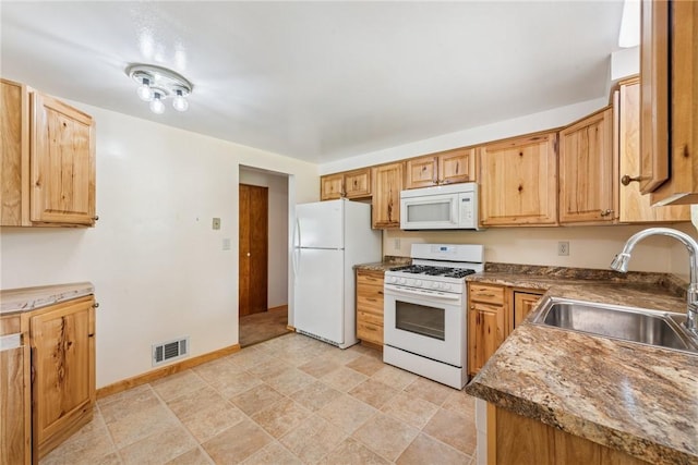 kitchen with white appliances, a sink, and baseboards