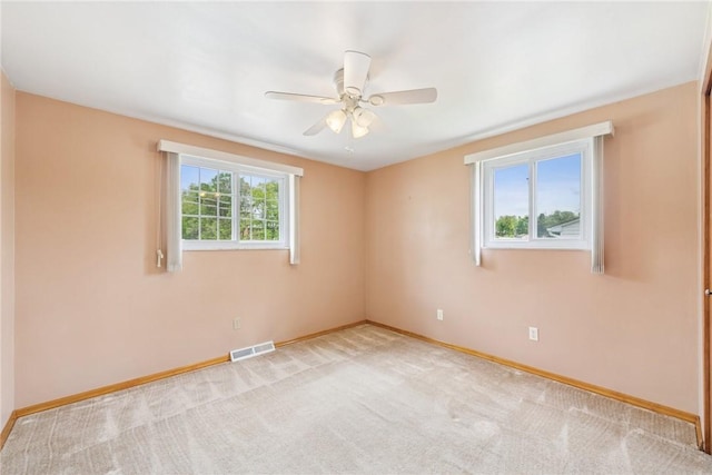 spare room with baseboards, a ceiling fan, and light carpet