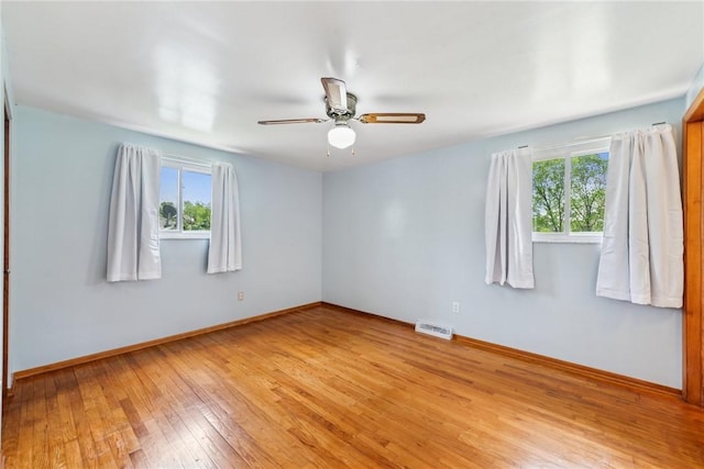 empty room with healthy amount of natural light, light wood-style floors, baseboards, and ceiling fan