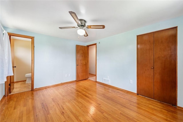 unfurnished bedroom with light wood-style flooring, connected bathroom, baseboards, a closet, and ceiling fan