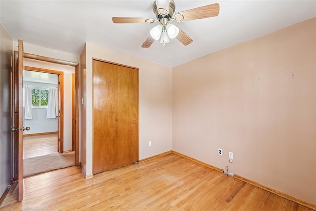unfurnished bedroom featuring light wood-type flooring, baseboards, a closet, and a ceiling fan
