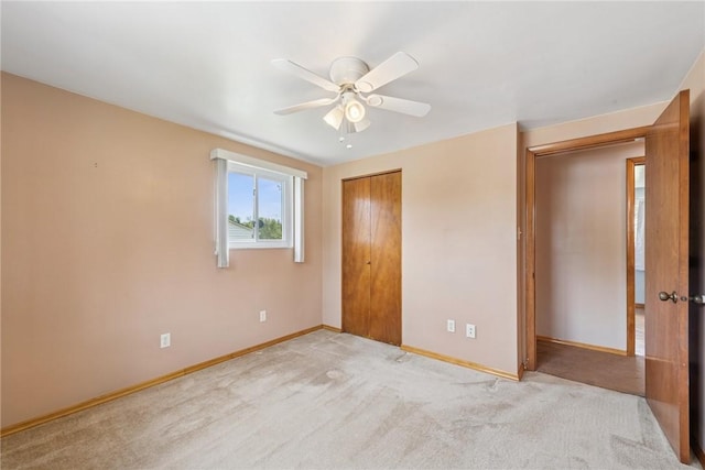 unfurnished bedroom with baseboards, a closet, carpet flooring, and ceiling fan