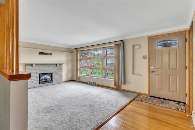 entryway with wood finished floors, a fireplace, and baseboards
