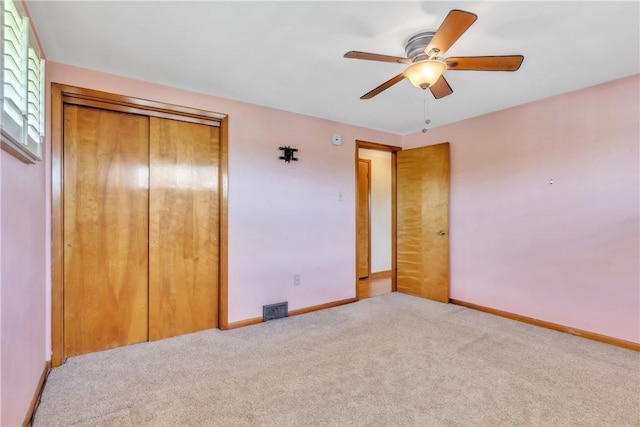 unfurnished bedroom with carpet flooring, a closet, baseboards, and a ceiling fan