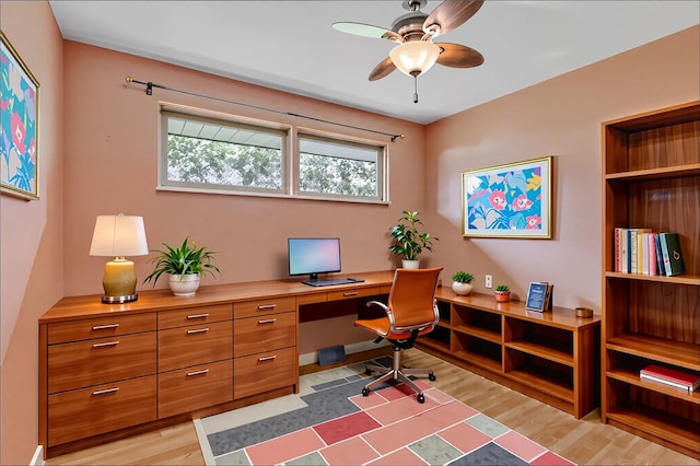 office area featuring plenty of natural light, a ceiling fan, built in desk, and light wood finished floors