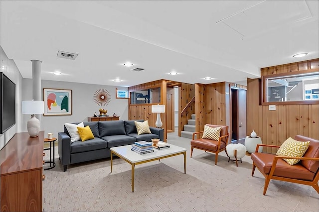 living room with wood walls, stairs, and light carpet