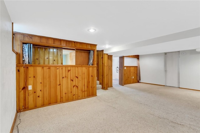 finished below grade area featuring wood walls, carpet, and baseboards