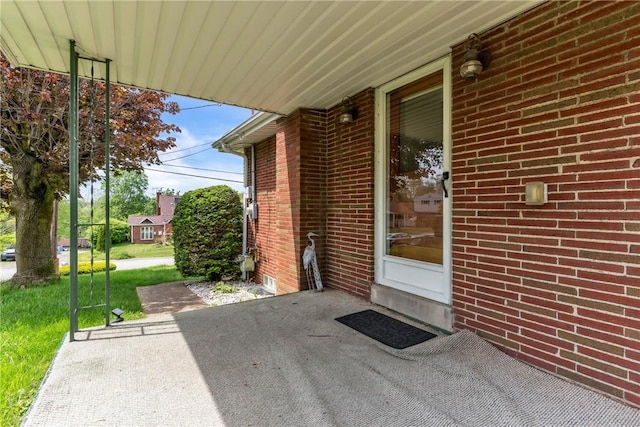 property entrance with a patio, brick siding, and a lawn