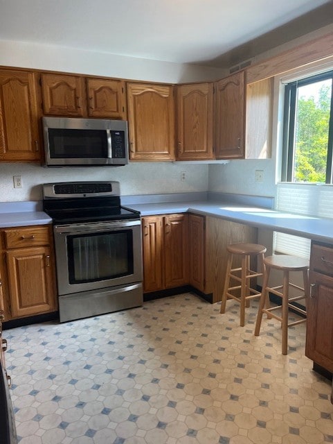kitchen featuring appliances with stainless steel finishes, light countertops, and brown cabinets