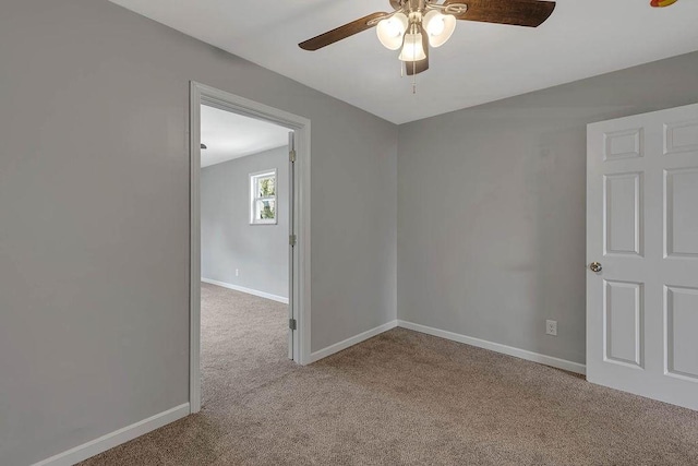 carpeted spare room featuring a ceiling fan and baseboards