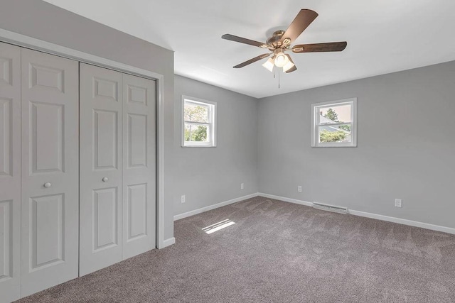 unfurnished bedroom with carpet, a closet, baseboards, and a ceiling fan
