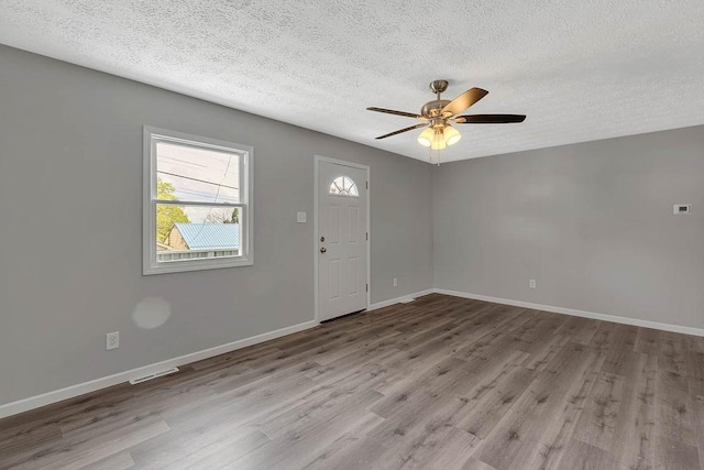 entrance foyer with a textured ceiling, wood finished floors, ceiling fan, and baseboards