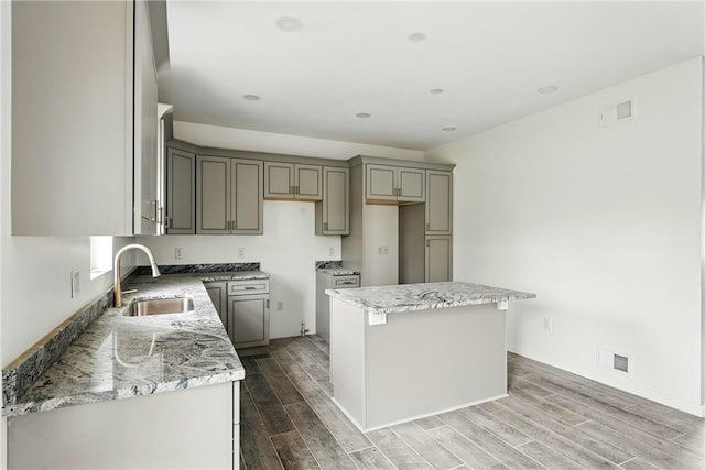 958 Cliff Mine Rd, Coraopolis, PA 15108 - kitchen with a sink, gray cabinets, wood finished floors, a center island, and light stone countertops