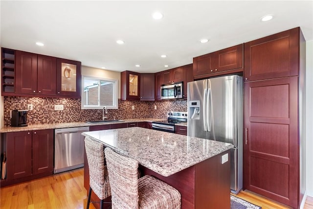 117 Teal Dr, Kennedy Twp, PA 15136 - kitchen featuring stainless steel appliances, a sink, glass insert cabinets, light wood-style flooring, and tasteful backsplash