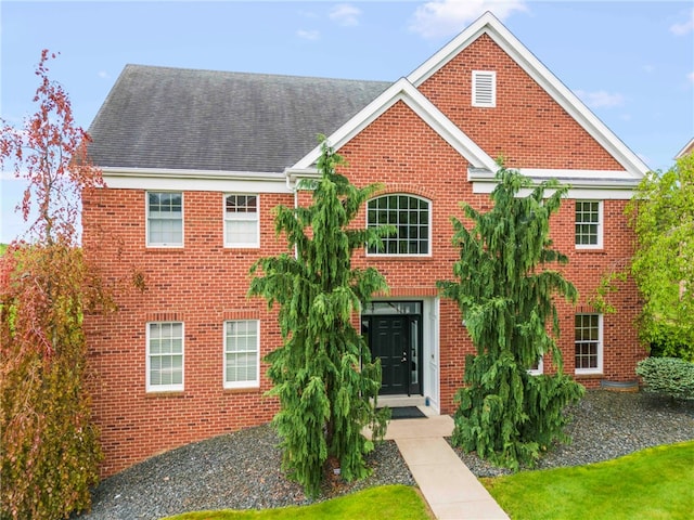 traditional-style home featuring brick siding and a shingled roof