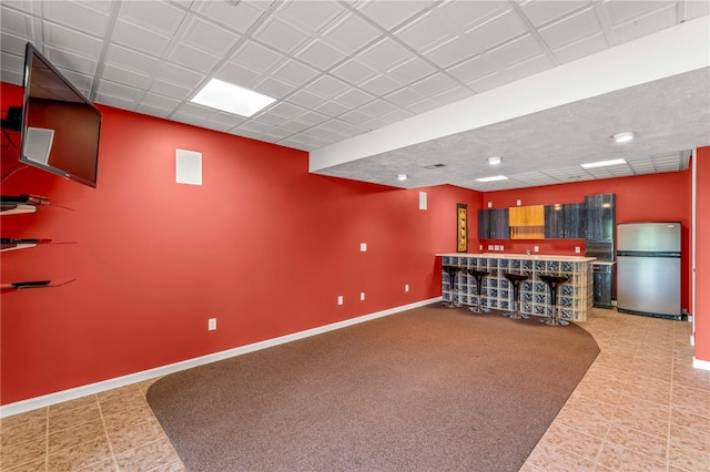 indoor dry bar with freestanding refrigerator, baseboards, and tile patterned floors