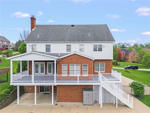 back of house with a patio area, brick siding, a chimney, stairway, and a yard