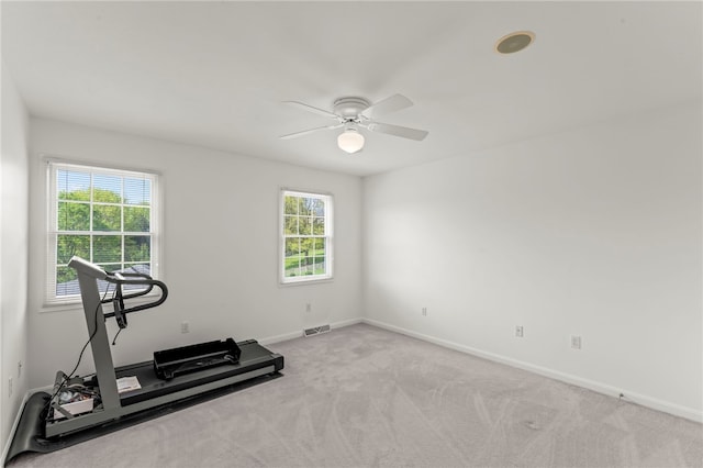 exercise room with ceiling fan, baseboards, and light colored carpet
