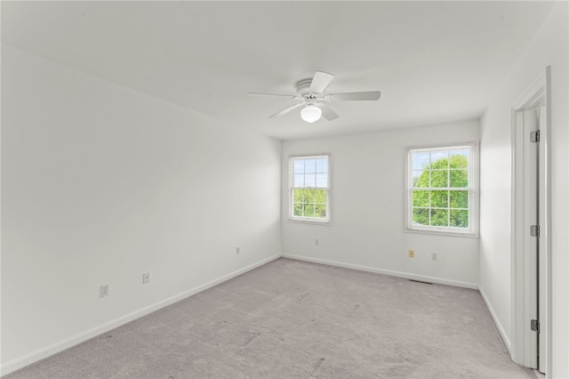 empty room with baseboards, a ceiling fan, and light colored carpet