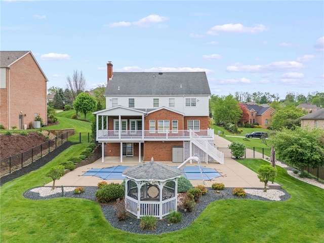 rear view of property featuring a patio area, brick siding, a chimney, a deck, and stairs