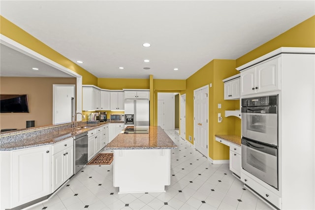 kitchen with appliances with stainless steel finishes, stone counters, a kitchen island, white cabinetry, and recessed lighting